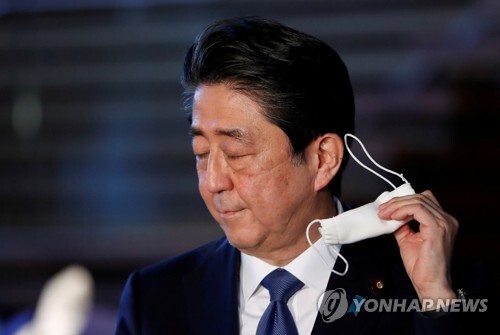 아베 신조 일본 총리가 6일 도쿄의 총리 관저에서 기자회견에 앞서 마스크를 벗고 있다. 아베 총리는 도쿄와 오사카 등 7개 지역을 대상으로 7일 긴급사태선언을 발령할 예정이다. [사진=로이터/연합뉴스]