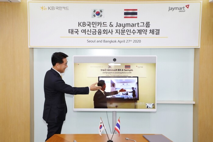 27일 서울 종로구 KB국민카드 본사에서 온라인 화상 계약 방식으로 진행된 태국 여신전문금융회사‘제이 핀테크(J Fintech)’지분 인수 계약식 후 이동철 KB국민카드 사장(왼쪽)과 아디삭 수쿰비타야(Adisak Sukumvitaya) ‘제이마트 그룹(Jaymart Group)’ 회장이 화상으로 악수하고 있다.(사진=KB국민카드)