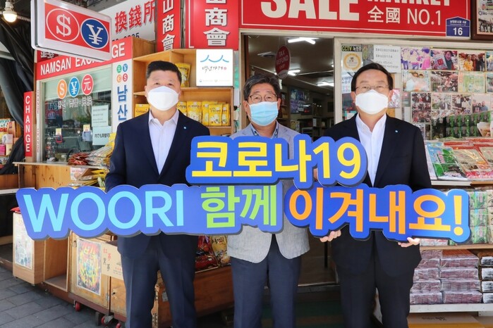 손태승 우리금융그룹 회장(사진 오른쪽)과 권광석 우리은행장(사진 왼쪽)이 서울 중구 소재 남대문시장에서 물품구매 후 박칠복 남대문시장 남산상회 대표와 코로나19 극복을 다짐하며 기념촬영을 하고 있다.(사진=우리금융그룹)