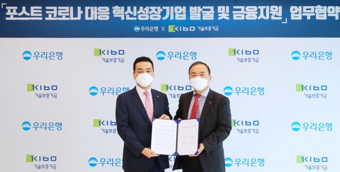 우리은행(은행장 권광석)은 22일 서울 중구 우리은행 본점에서 기술보증기금과 ‘포스트 코로나 대응 혁신성장기업 발굴 및 금융지원’업무협약을 체결했다. 강신국(왼쪽) 우리은행 IB그룹장 겸 우리금융그룹 CIB총괄이 백경호 기술보증기금 상임이사와 기념촬영을 하고 있다.(사진=우리은행)