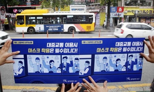 25일 오후 광주 전남대학교 후문 버스 승강장에서 북구청 안전총괄과 직원들이 '대중교통 이용 시 마스크 착용은 필수입니다'라는 문구가 적힌 홍보물을 부착하고 있다. [사진= 광주 북구청 제공]