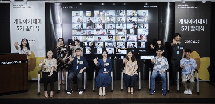 지난 27일 열린 넷마블문화재단 게임아카데미 5기 발대식에서 학생들이 각오를 적은 플랜카드를 드는 퍼포먼스를 온라인으로 하고 있다. 현장에 참가한 관계자들은 5기를 표현한 손동작과 함께 기념촬영을 하고 있다.(사진=넷마블)
